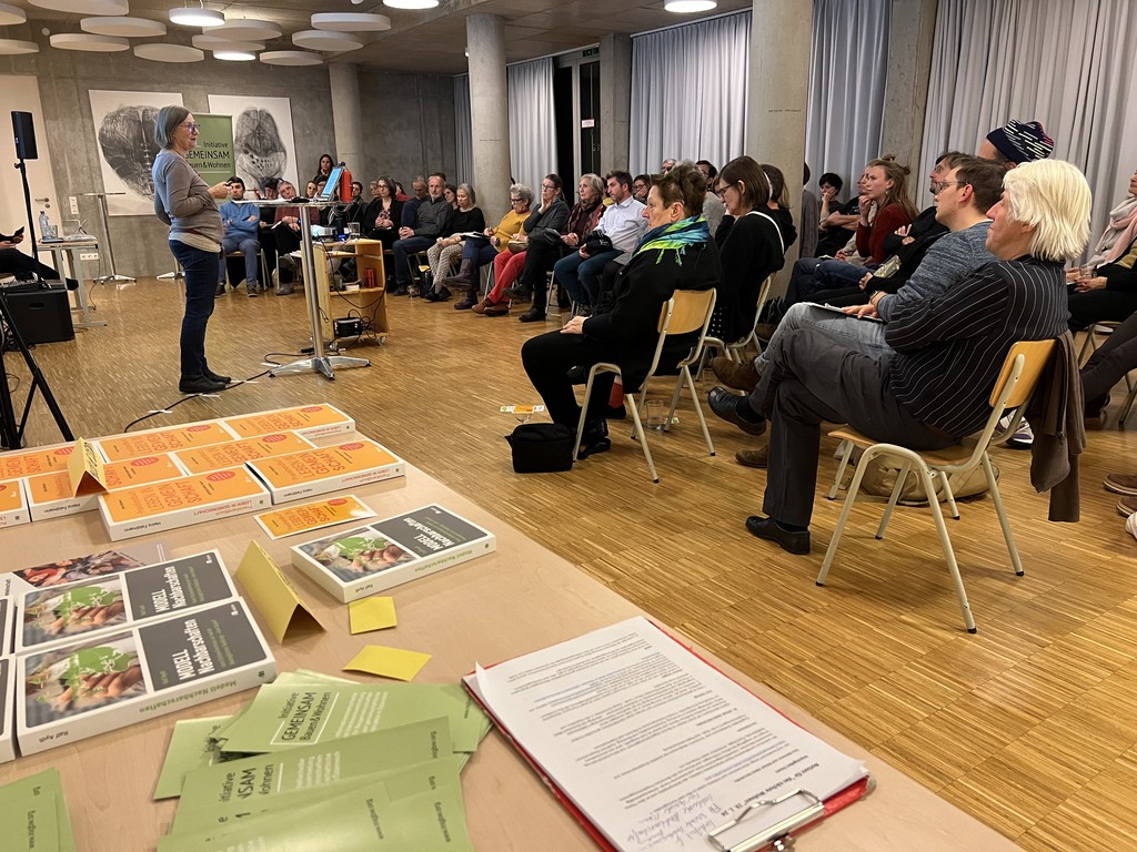 Publikum im vollbesetzten Raum des Wohnprojekts Wien