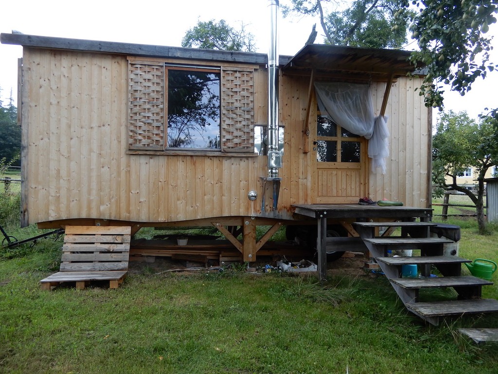 Kleines Holzhaus auf Stehern mit Zugangstreppe auf Wiese