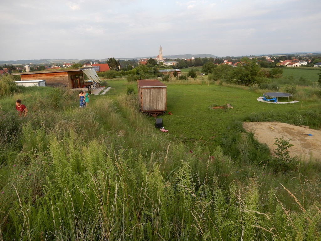 Weitblick von oben auf großes Gartengelände mit Rasen und Trampolin
