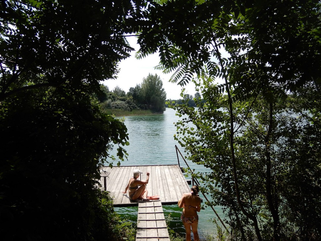 Frauen in Badekleidern sonnen sich auf Holzsteg vor Badeplatz