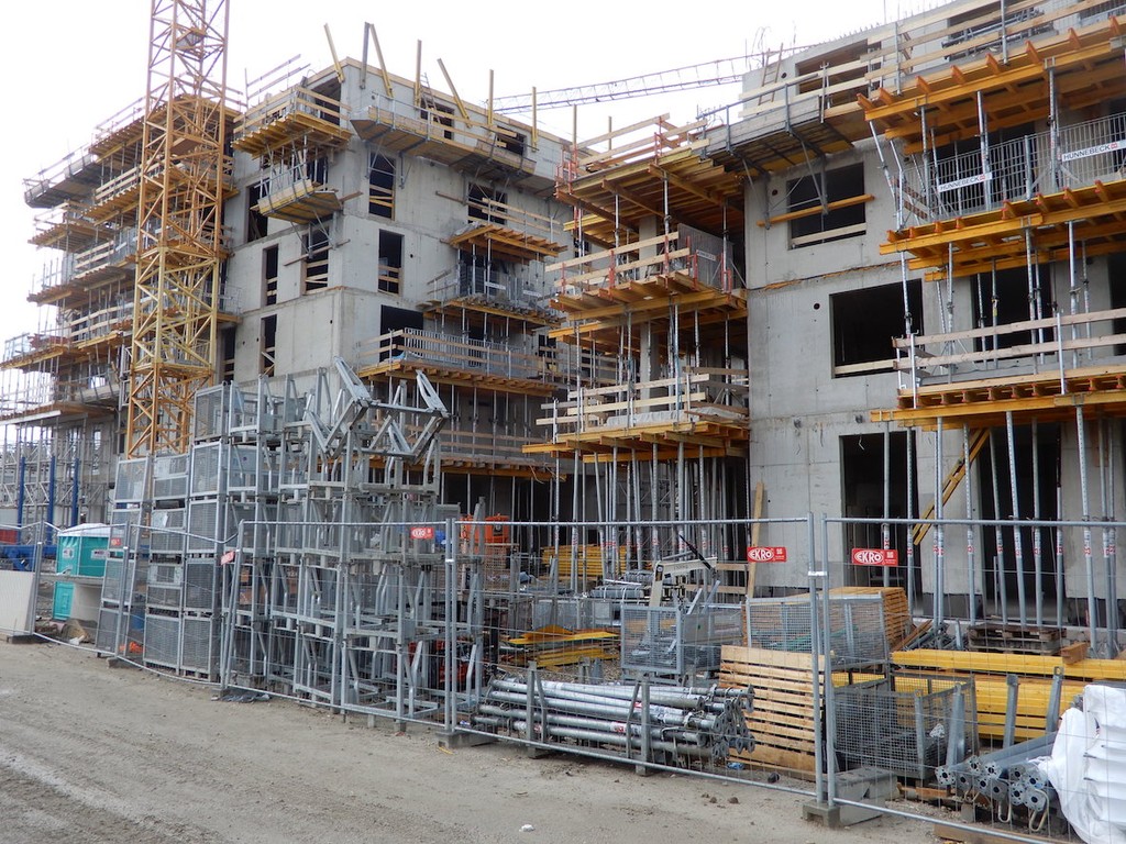 Eingezäunter Rohbau aus Beton mit Baugerüsten